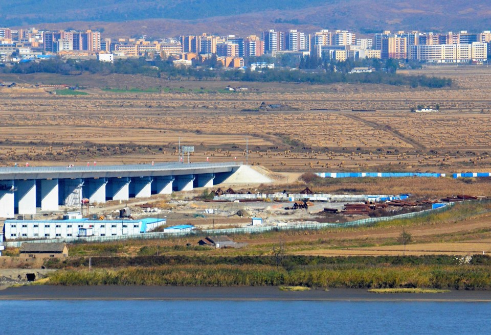 The North Korean side of a newly constructed bridge over the Yalu River, with a town in the distance.