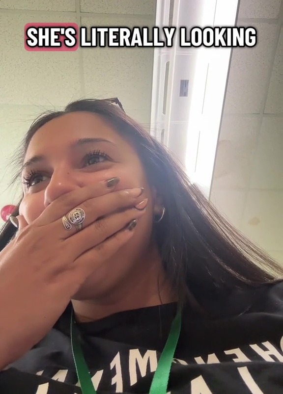 A woman covers her mouth with her hand and looks upward with a text overlay that says "SHE'S LITERALLY LOOKING".