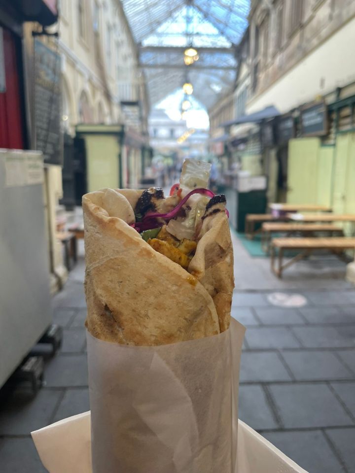 Kebab in a pita with red onion, lettuce, and chicken.