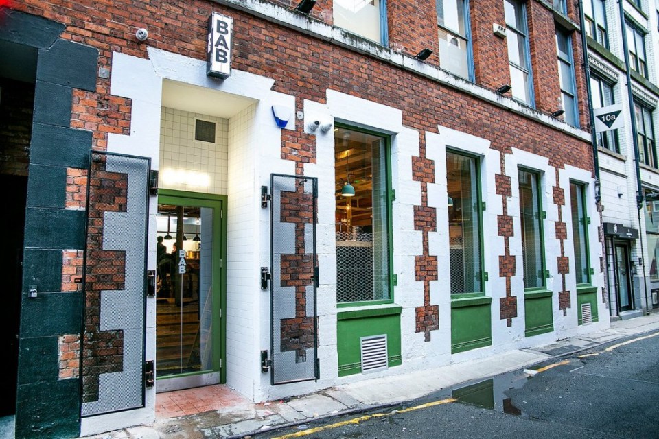 The exterior of Bab restaurant in Manchester with a brick facade and white and green accents.