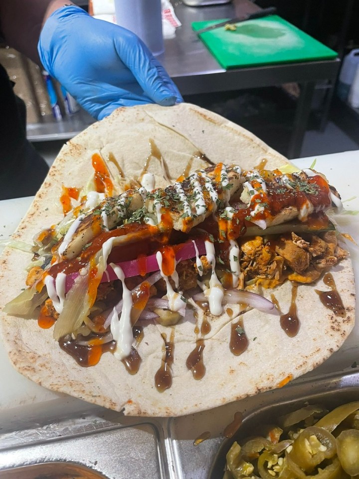 A falafel kebab from Falafel Guys, with white sauce, red chili sauce, and brown sauce on a flatbread.