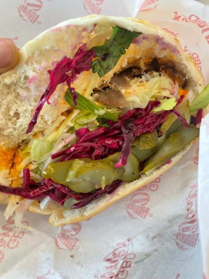 Kebab with meat, lettuce, pickled cabbage, and pickles in a pita.