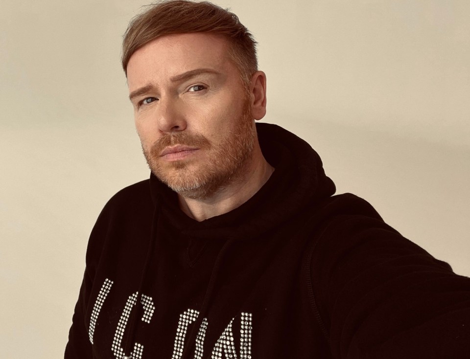 Mikey Phillips, a makeup artist, wearing a black hoodie with a diamond-like pattern on it.