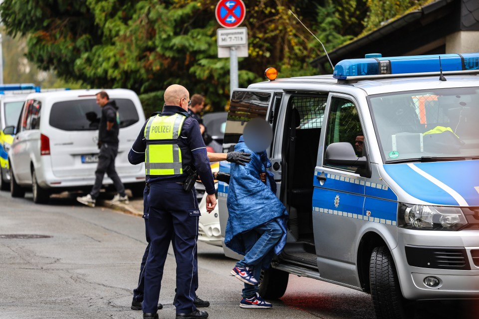 Police officers bring a teenager to a police car.