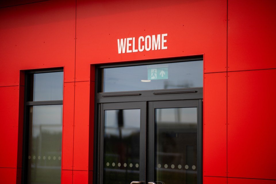 Welcome sign on a red building at Carrington Training Ground.