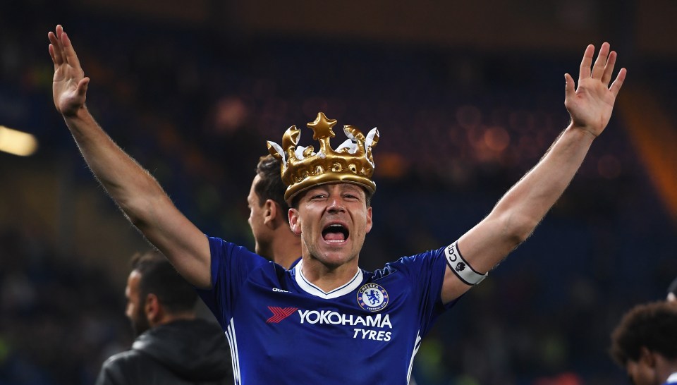 John Terry of Chelsea celebrates with an inflatable crown, arms raised, after a Premier League match.