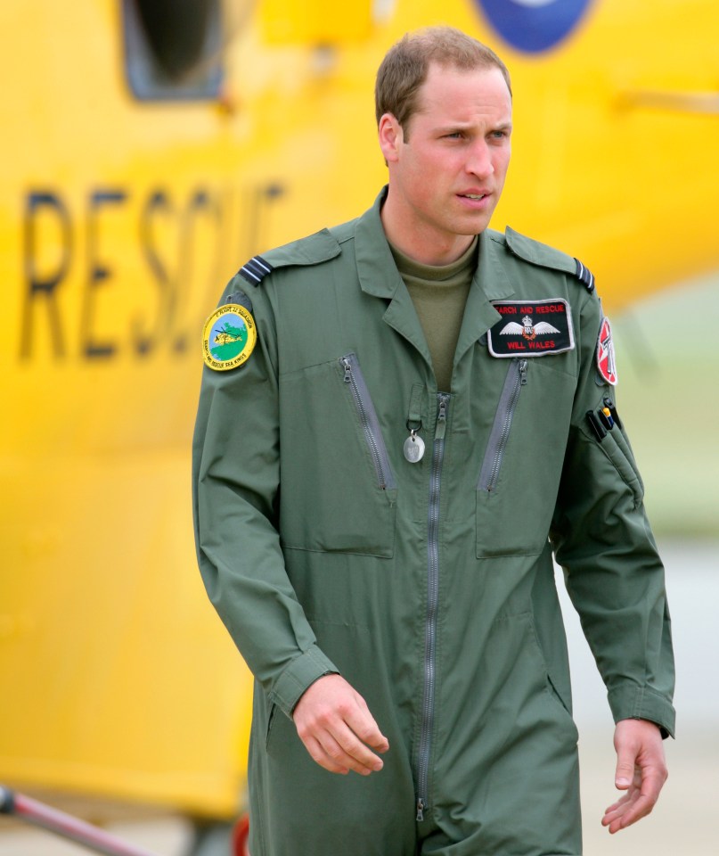 Prince William in an RAF Search and Rescue flight suit, with a yellow helicopter behind him.