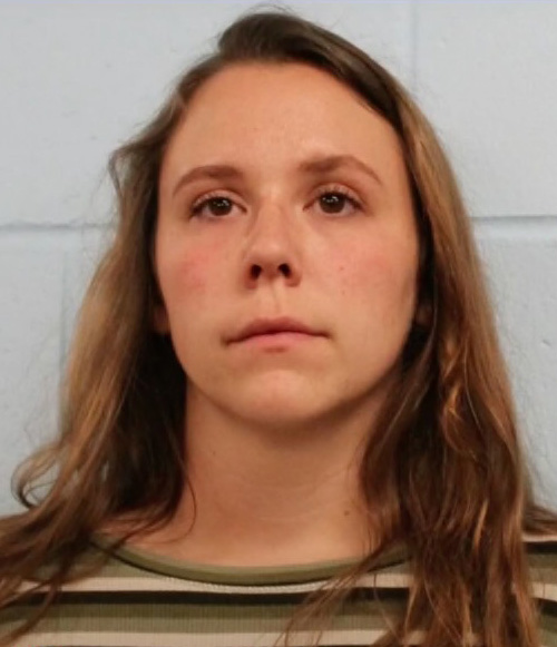 the woman is wearing a striped shirt and looking at the camera .