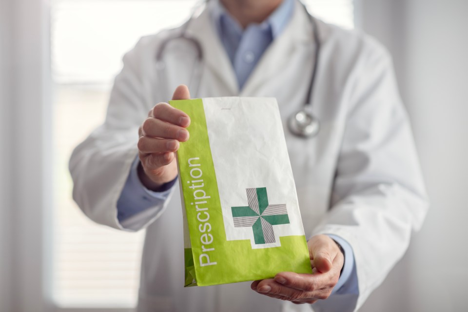 A doctor or pharmacist handing over a paper bag labeled "Prescription" with a green cross symbol.