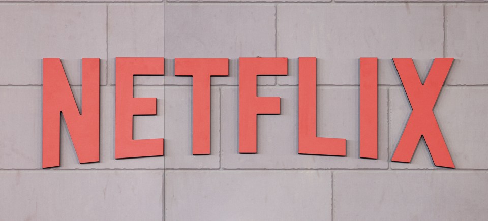Red Netflix sign on a white brick wall.
