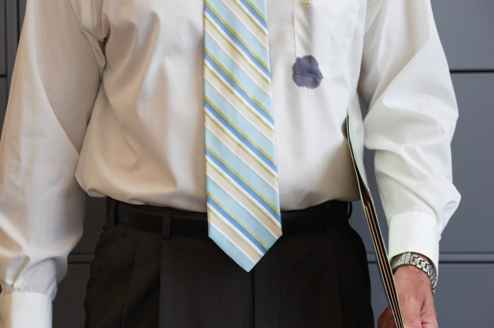 A businessman in a white shirt and striped tie with an ink stain on his shirt pocket.