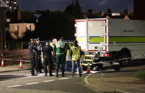 Emergency services personnel gathered at night around a bomb disposal truck.