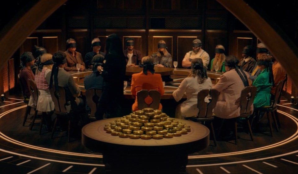 A group of blindfolded people seated around a circular table with a pile of golden coins in the center.