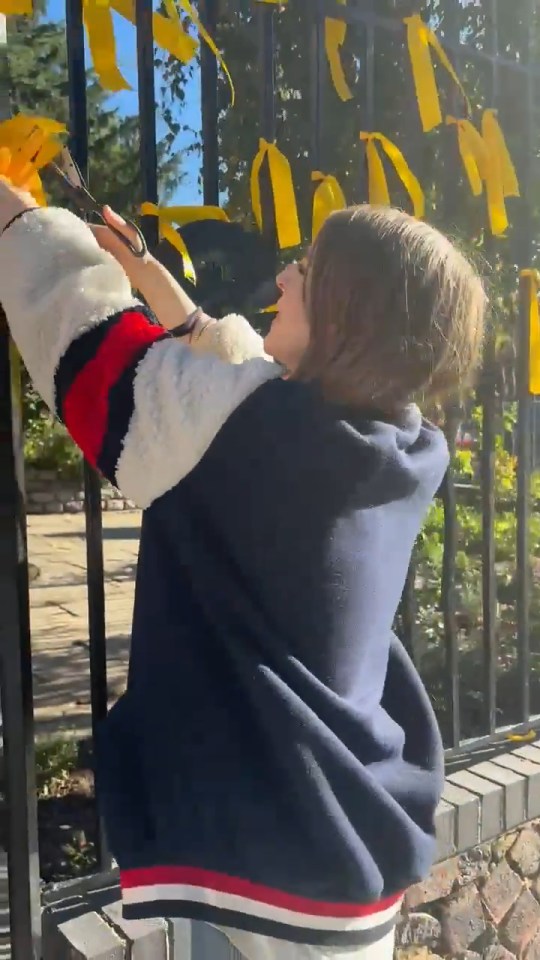 Nadia Yahlom cutting down yellow ribbons tied to a fence.