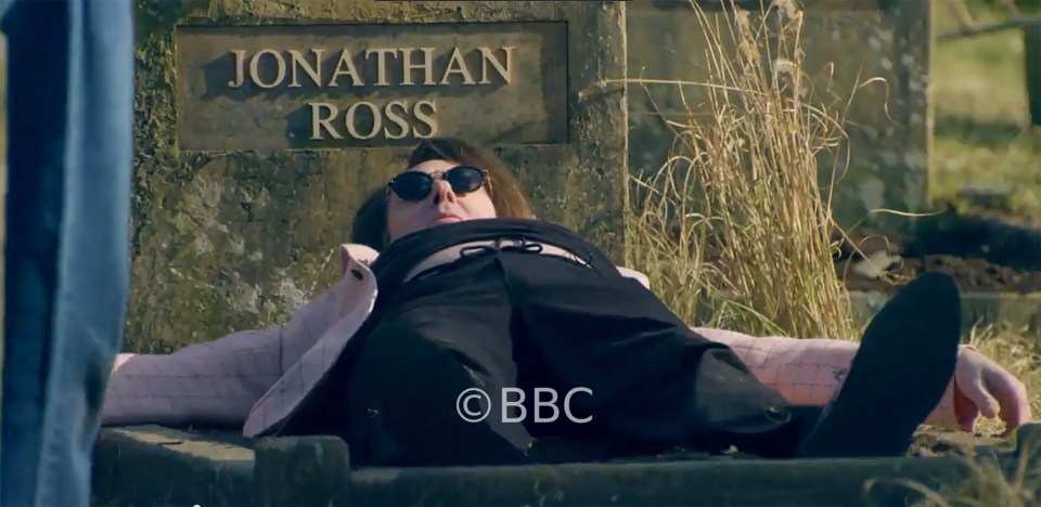 Jonathan Ross laying on a stone slab with the name "Jonathan Ross" carved above him.