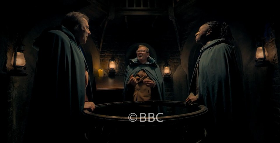 Jonathan Ross, Alan Carr, and Cat Burns in a dungeon-like room.