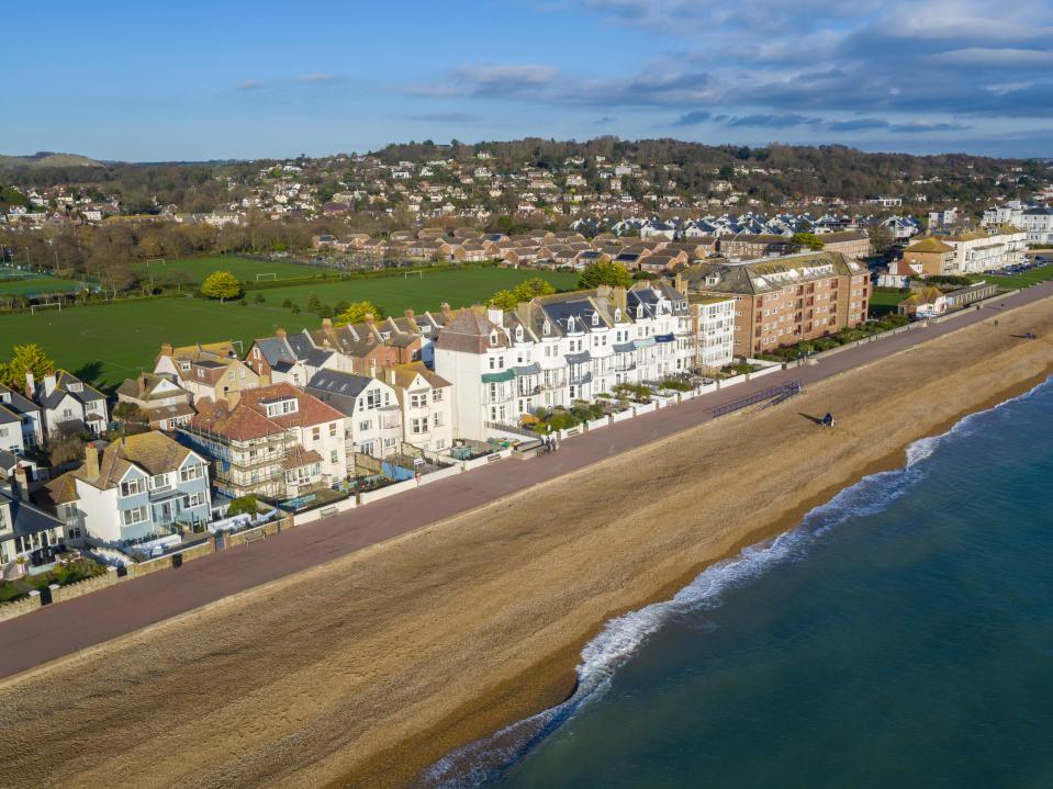 Aerial view of Marine Parade in Hythe, Kent, featuring beachfront homes, the sea, and rolling hills in the background.