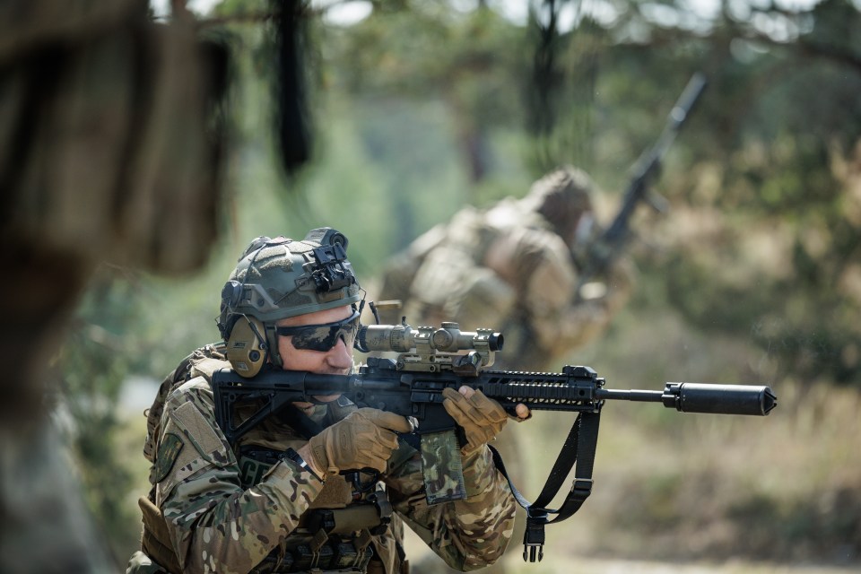 Ukrainian serviceman and former tennis player Sergiy Stakhovsky aiming an assault rifle with another soldier in the background.