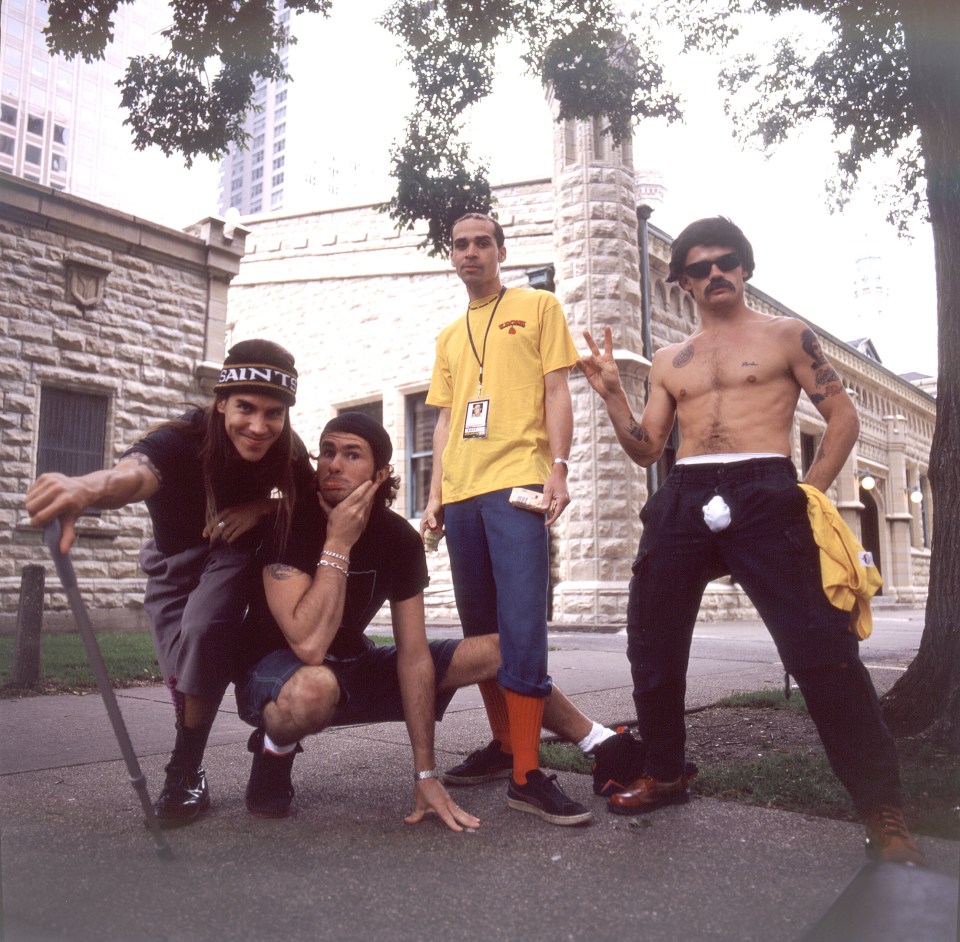 Red Hot Chili Peppers band members Anthony Kiedis, Chad Smith, Arik Marshall, and Flea pose outdoors.