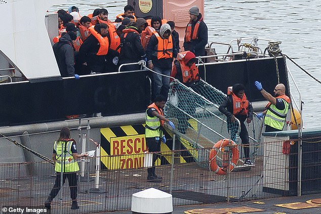 Migrants wearing lifejackets disembark from the Border Force catamaran, Typhoon, on Wednesday after being picked up from dinghies in the middle of the Channel