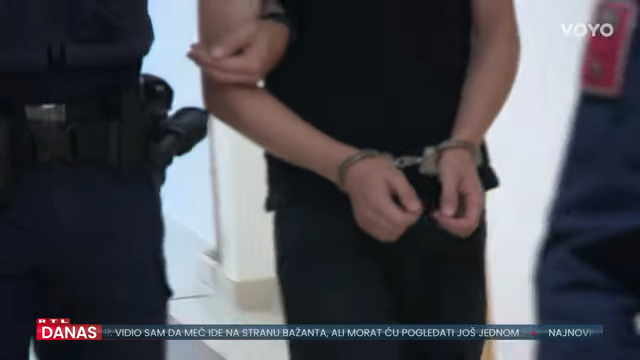 A person in handcuffs being led away by a law enforcement officer.