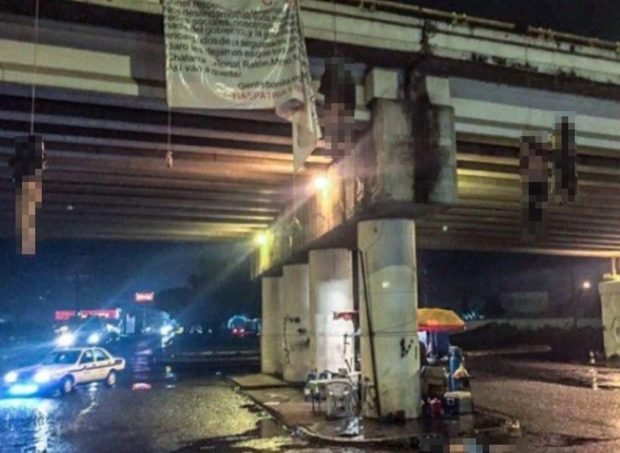 Bodies hanging from an overpass in Mexico, with a banner partially visible.