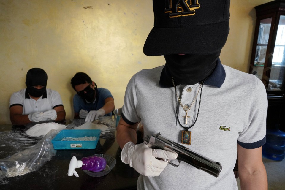 Guero, a Sinaloa Cartel member, holds a pistol while two other members prepare drugs in a safe house.