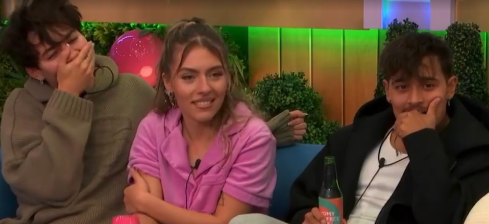 Three people laughing, with two covering their mouths.