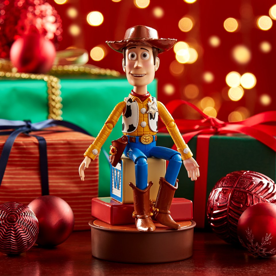Woody toy from Toy Story sitting on blocks, surrounded by Christmas presents and ornaments.