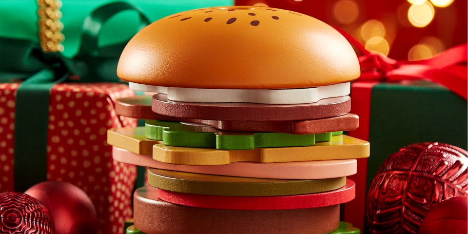 A wooden toy hamburger, surrounded by Christmas gifts and ornaments.