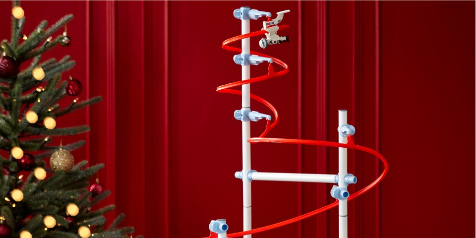 A car toy on a track next to a Christmas tree.