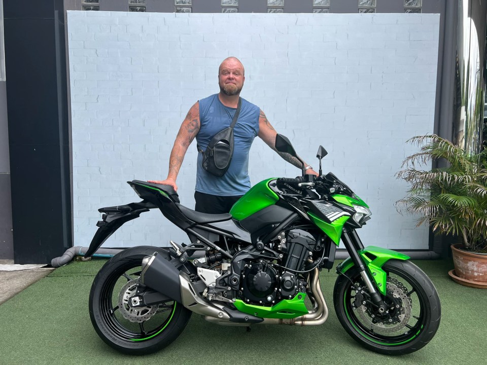 Craig Davies standing next to a green Kawasaki motorbike.