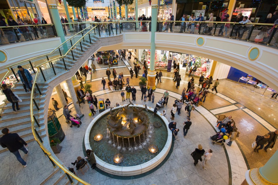 Shoppers filling a large, multi-story mall, decorated for Christmas.