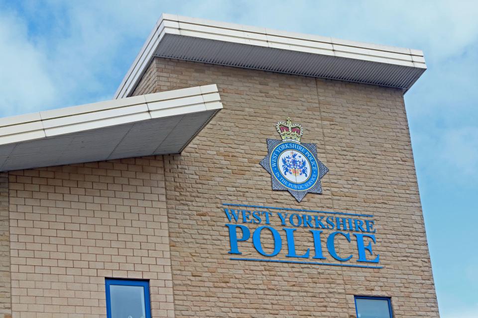 The West Yorkshire Police sign and crest on a brick building in Bradford, UK.