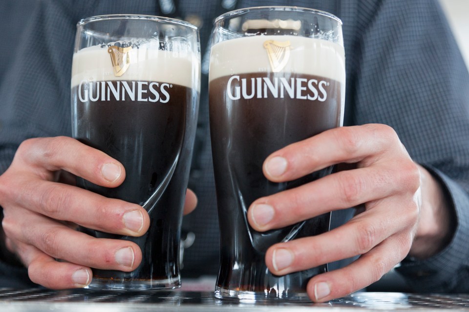 Two hands holding pints of Guinness.