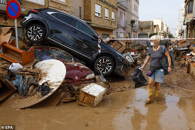 People walk past piled up debris in the flood-hit municipality of Catarroja, Valencia province, Spain, 05 November 2024