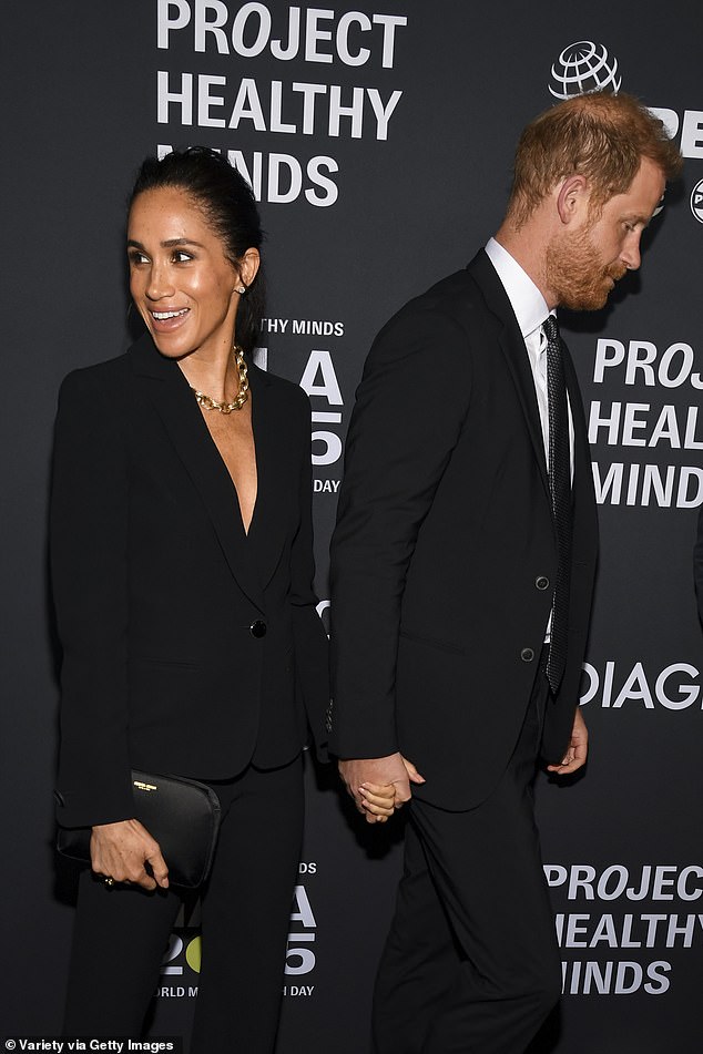 Meghan smiled at someone as Harry edged away