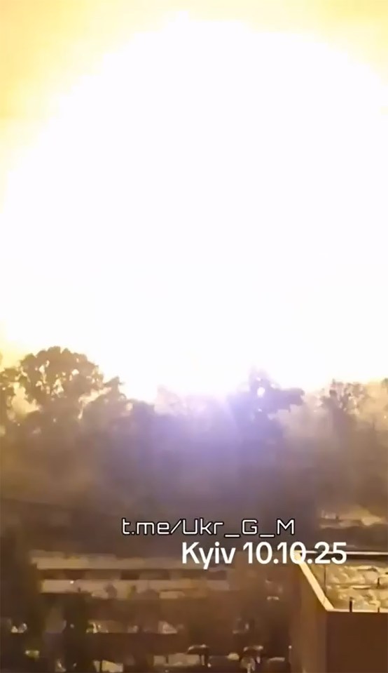 Firefighters at night in a city street covered in debris, with a building on fire and a tall apartment building in the background.