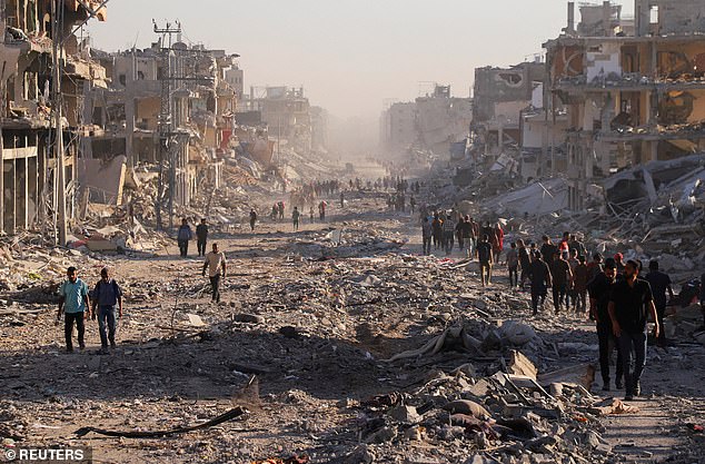 Palestinians walk through a damaged neighborhood in the aftermath of an Israeli operation, after Israel's government ratified a ceasefire with Hamas, in Gaza City October 10