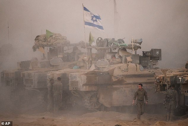 Israeli soldiers stand near their tanks along the Israeli-Gaza border, as seen from southern Israel, Friday, Oct. 10, 2025, after Israel and Hamas have agreed to a pause in their war and the release of the remaining hostages