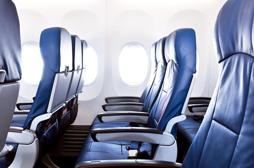 Empty blue seats in an airplane cabin with windows.