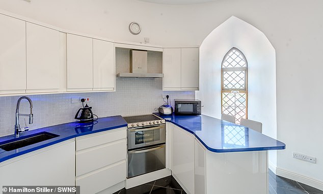 In the kitchen (pictured), stainless steel fixtures are complemented by sleek white cupboards, black tiling and a quirky blue counter top