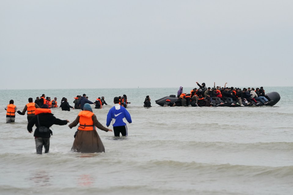 People thought to be migrants wade into the sea to board a small boat in Gravelines, France.