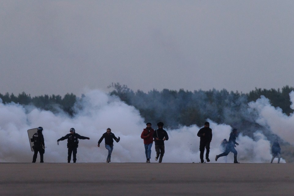 French police using tear gas to stop migrants boarding boats.