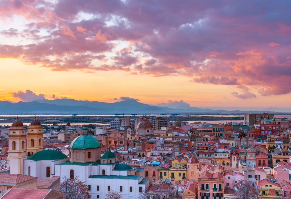Cagliari city panorama at sunset, with old houses and the Cathedral, view of mountains in the background.