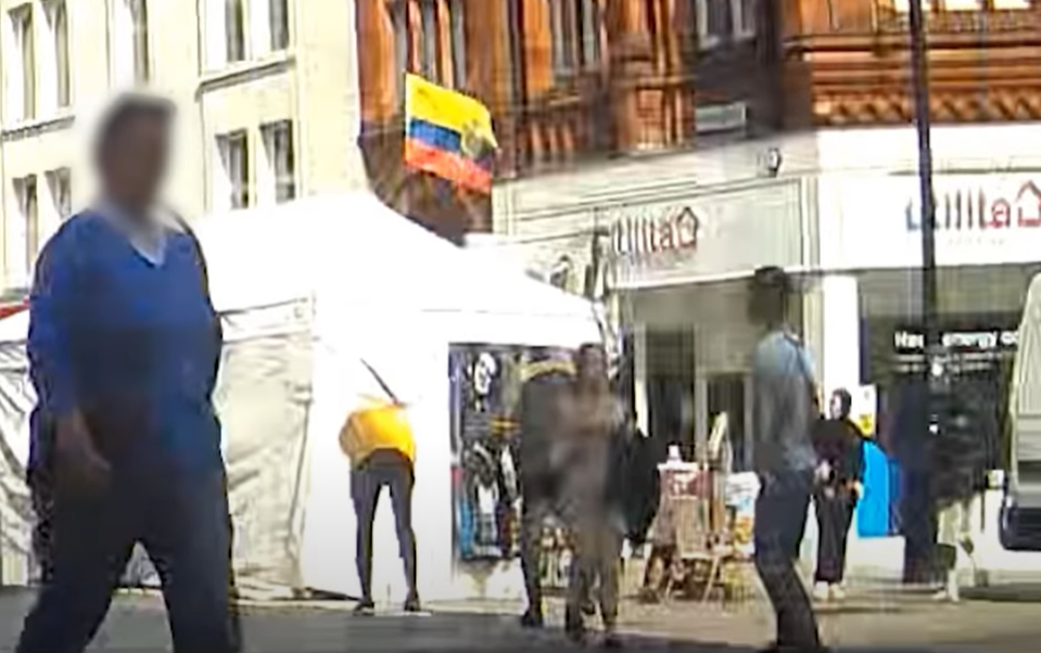 People walking on a street with tents and a flag of Colombia.