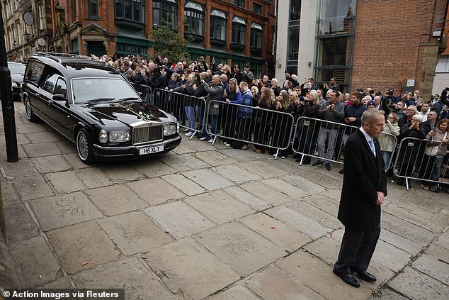 Mourners look on as the funeral cortege of Ricky Hatton passes by in Manchester today