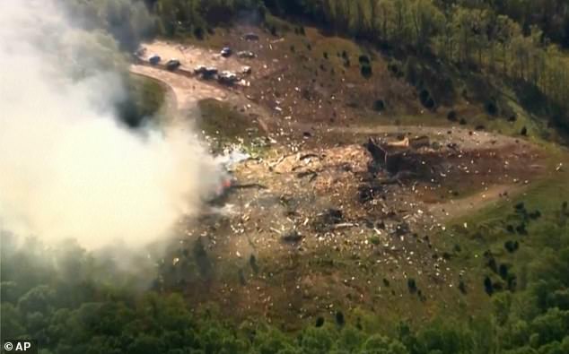Smoke fills the air as debris covers the ground and vehicles after a powerful blast ripped through a military explosives manufacturing plant