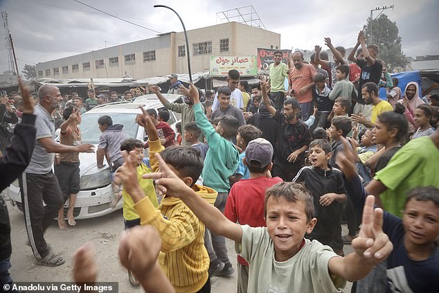 Palestinians, including children, gathered in the city of Khan Yunis celebrate after the announcement of the ceasefire agreement in Gaza on October 9, 2025