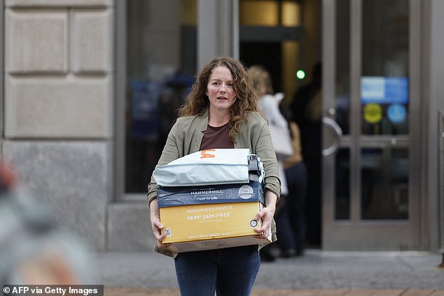 The White House budget office said Friday that mass firings of federal workers have started in an attempt to exert more pressure on Democratic lawmakers as the government shutdown continues. Pictured: A USAID worker carries out their belongings after being fired in February during the Elon Musk-led DOGE purge